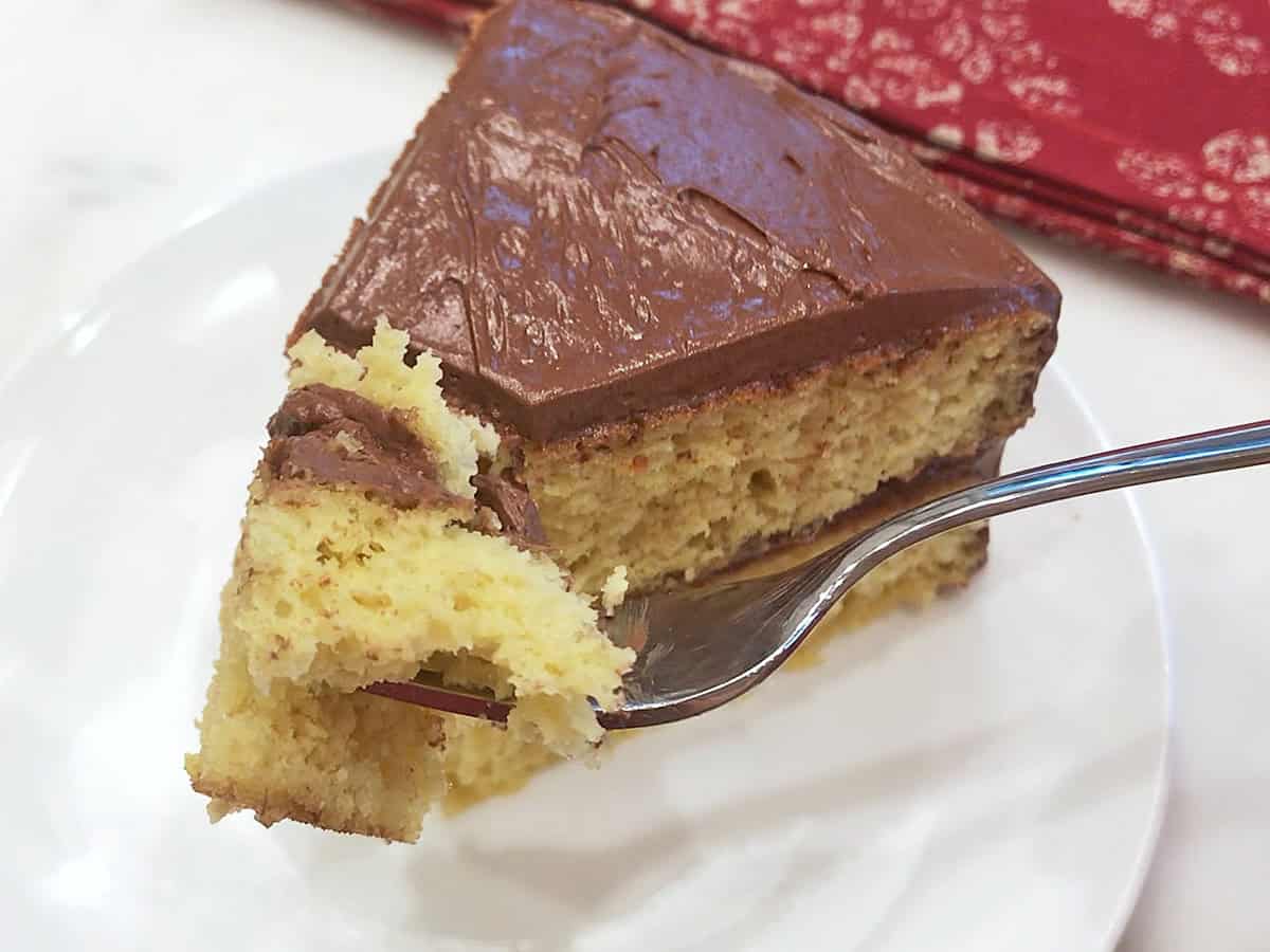 A fork is holding a piece of cake, showing off its tender crumb.