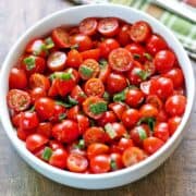 Cherry tomato salad is served in a white bowl.