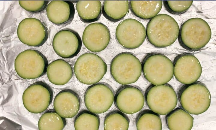 Zucchini slices on a foil-lined baking sheet.