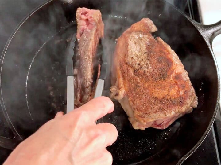 Cooking the edges of ribeye steaks.