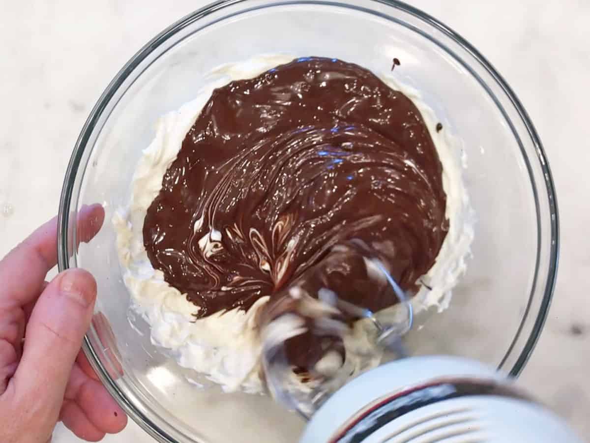 Adding melted chocolate to the cream cheese mixture.