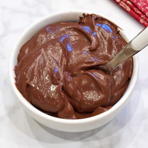 Avocado chocolate mousse is served in a white bowl with a spoon.