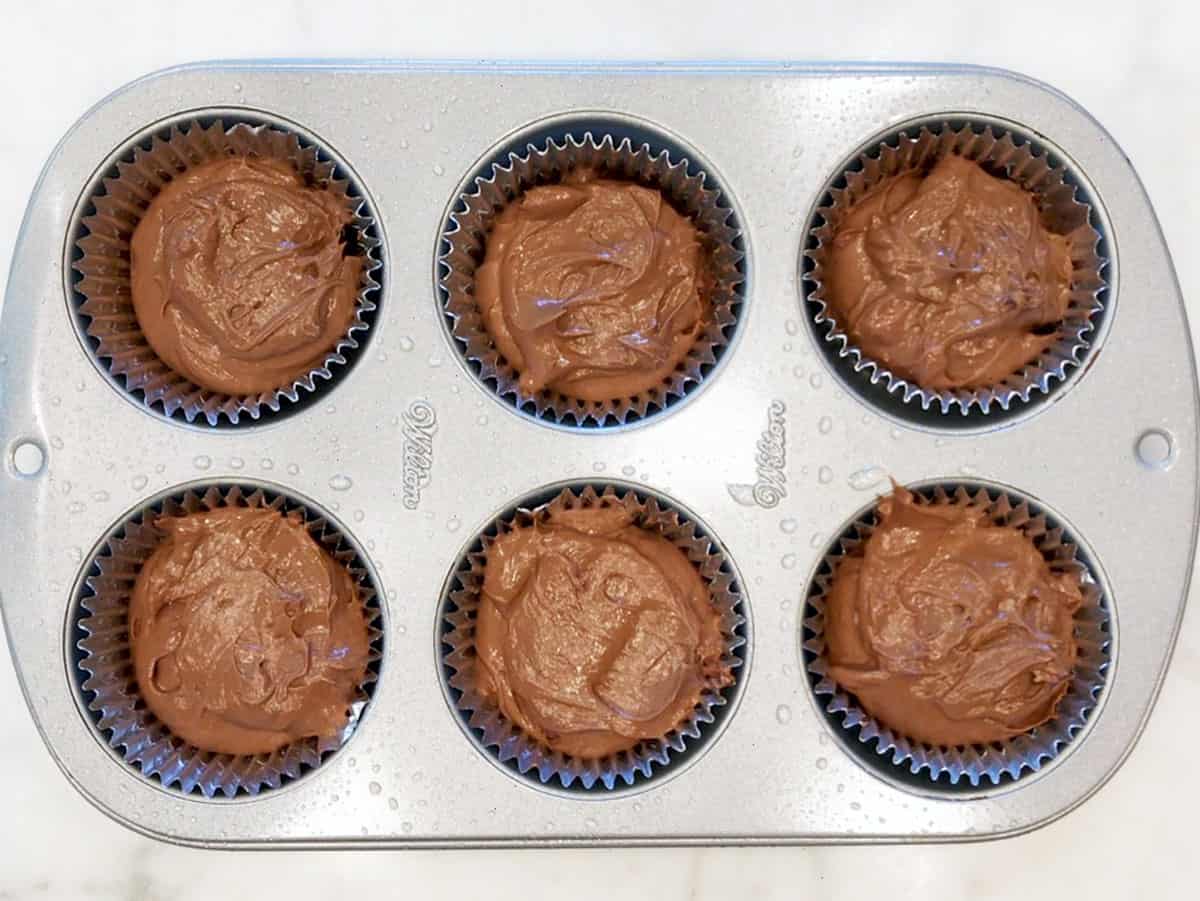 The cake mixture was divided between the muffin cups.