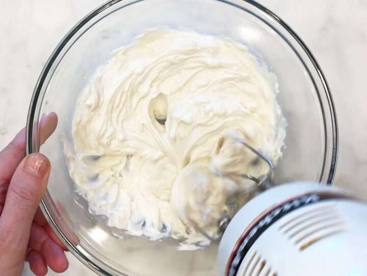 Whipping the cream cheese with a handheld electric whisk.