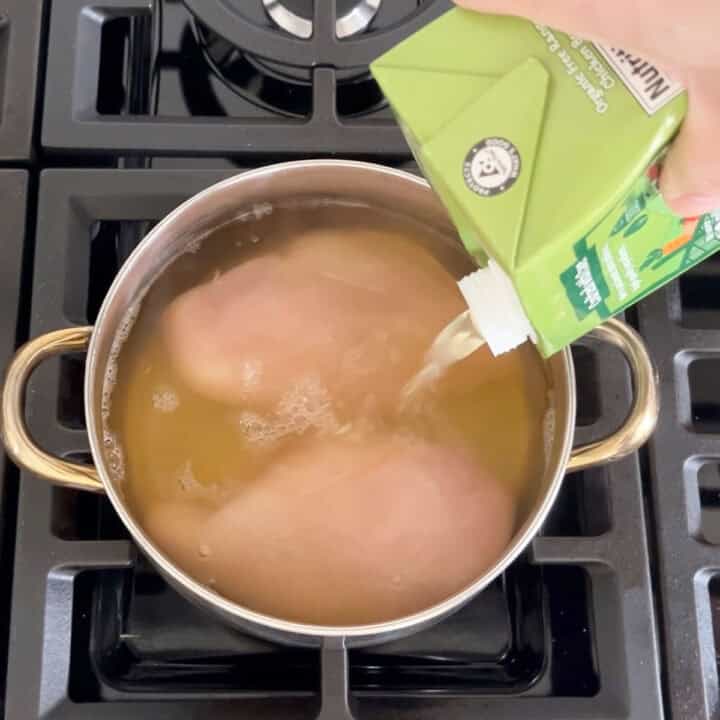 Adding broth to cover the chicken.