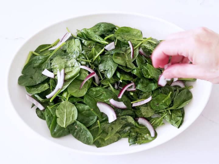 Adding sliced red onions to the salad.