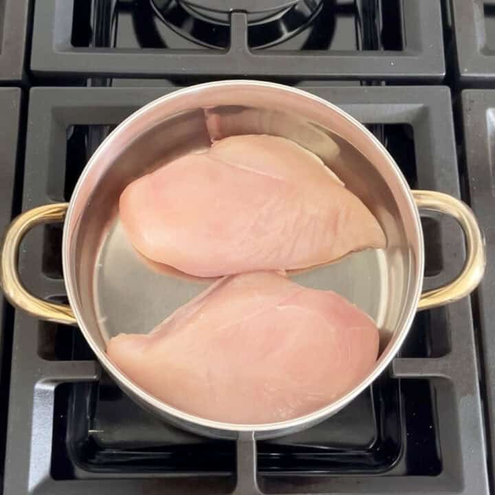 Two chicken breasts in a saucepan.