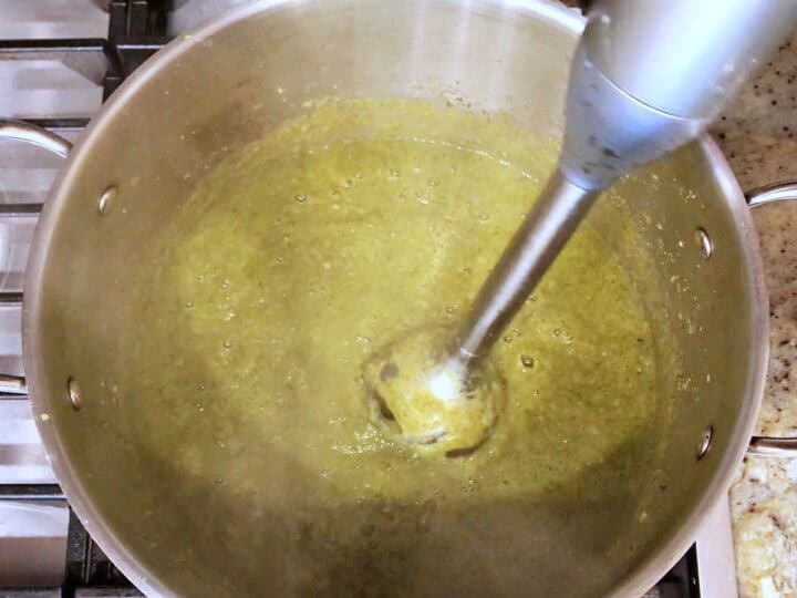 Blending the soup with an immersion blender.