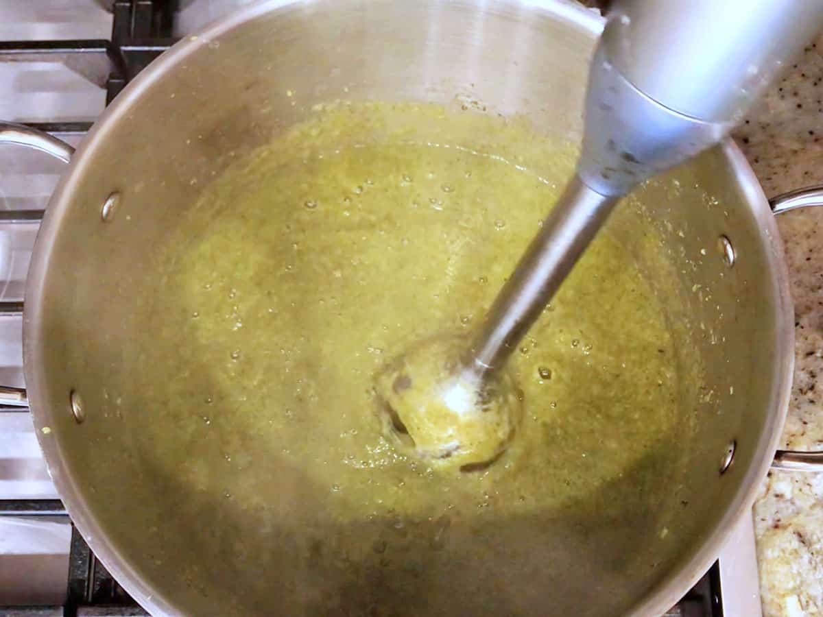 Blending the soup with an immersion blender.