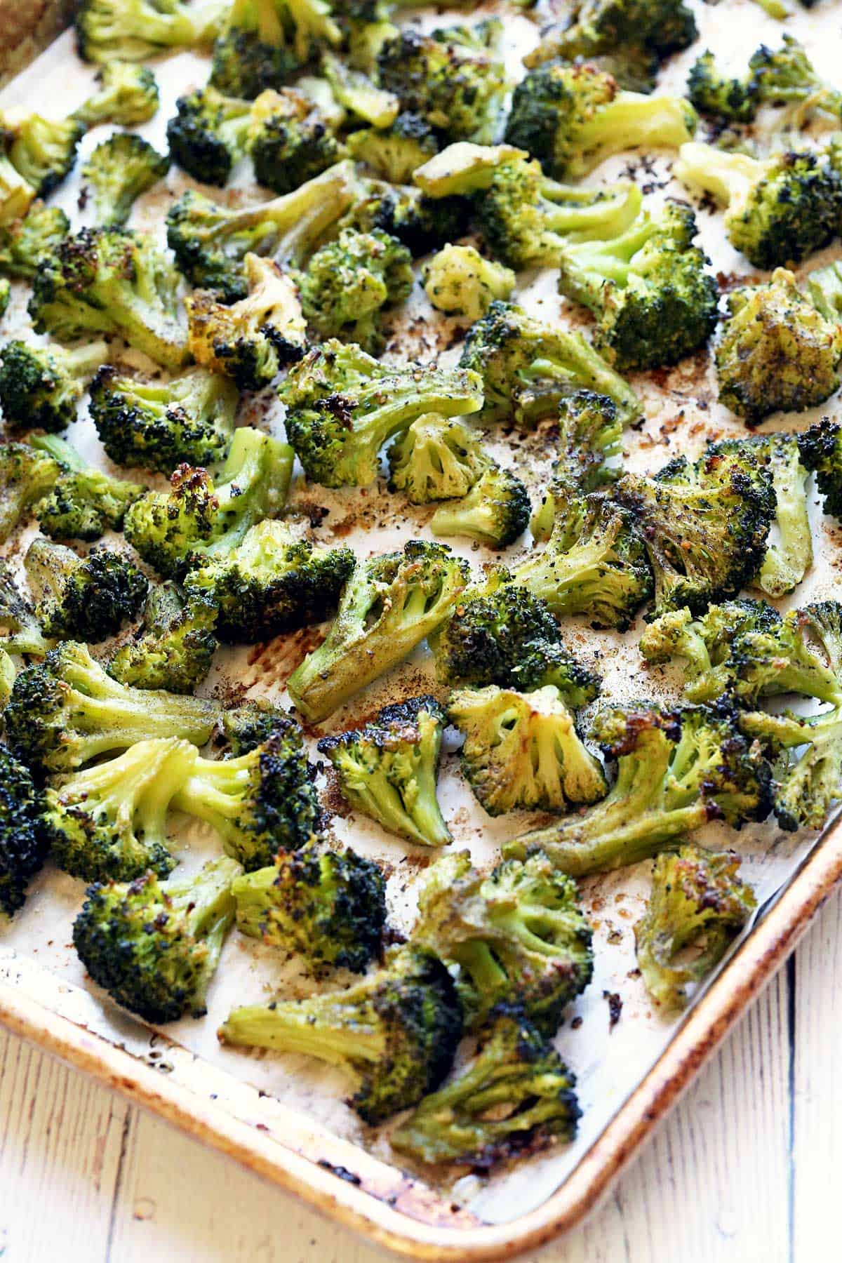 Roasted frozen broccoli on a parchment-lined baking sheet.