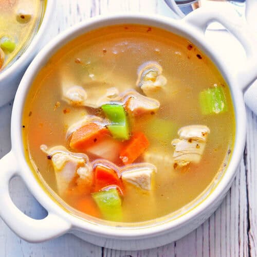 Turkey carcass soup is served in a white bowl.