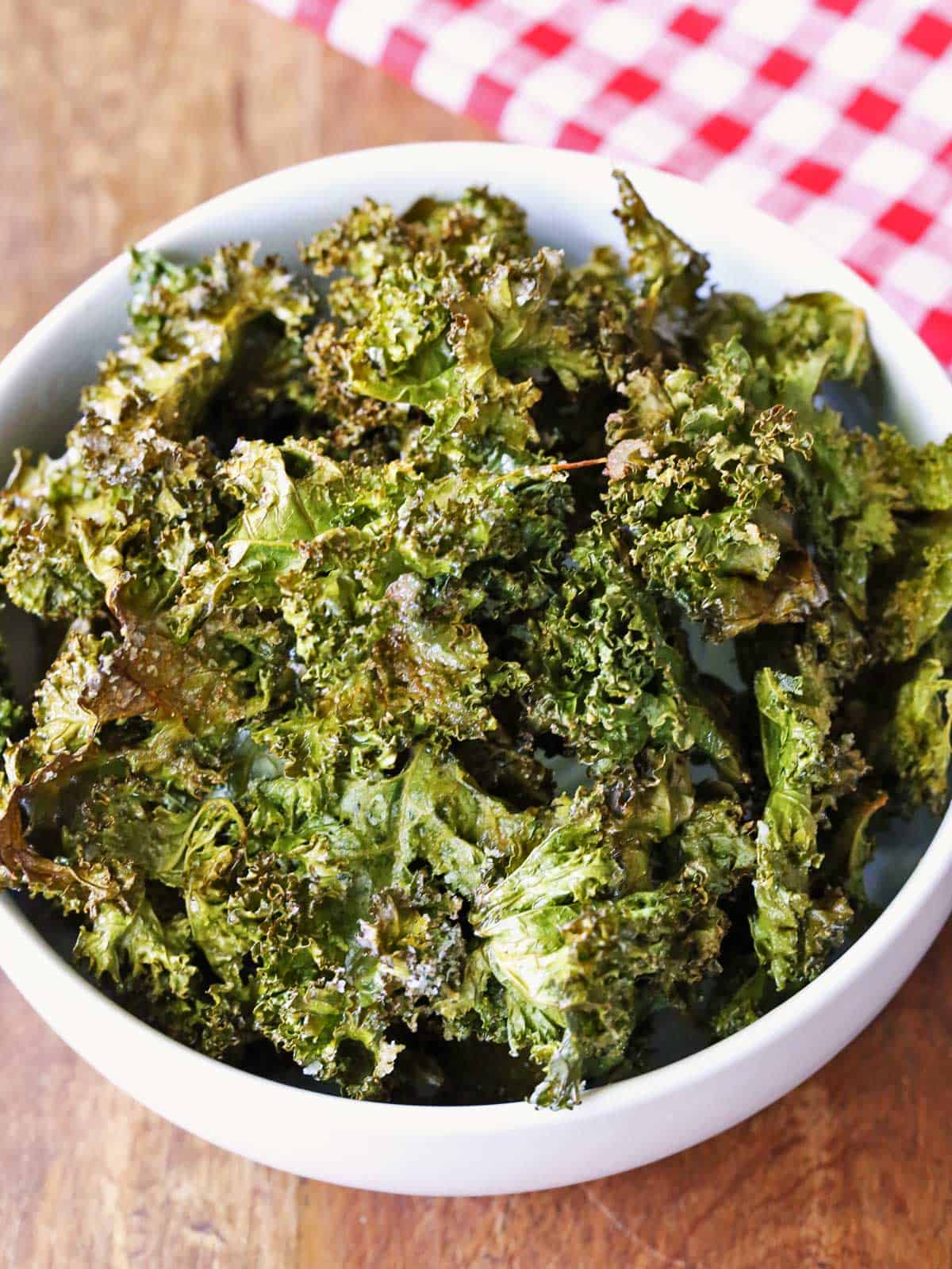 Kale chips are served in a white bowl.