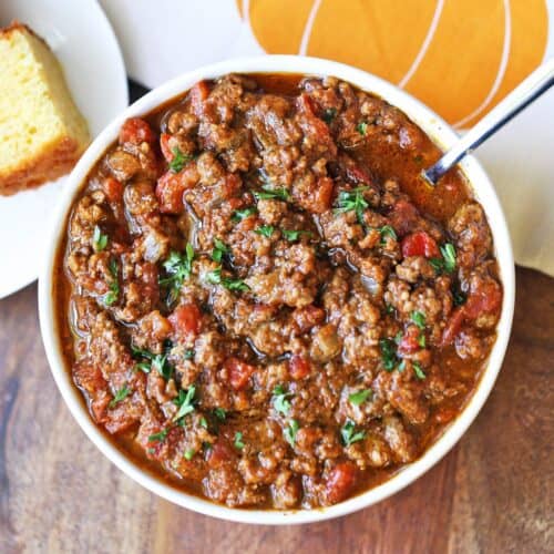 Pumpkin chili is served in a white bowl with cornbread.