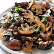 Roasted mushrooms are served on a white plate.