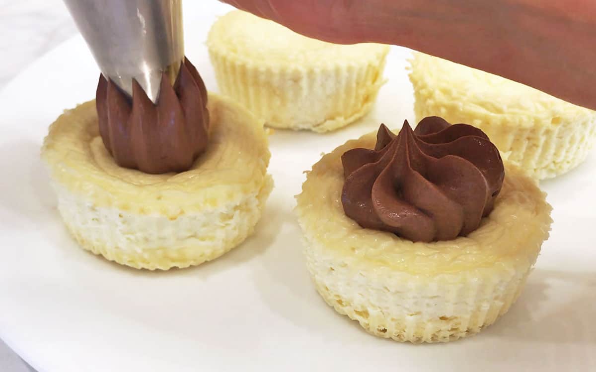 Topping the cakes with chocolate whipped cream.