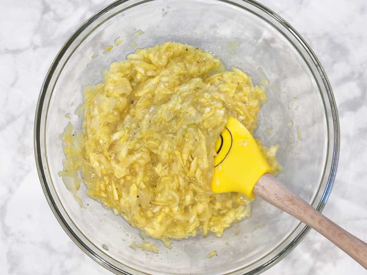 Mixing the egg, spices, squash, and onions.