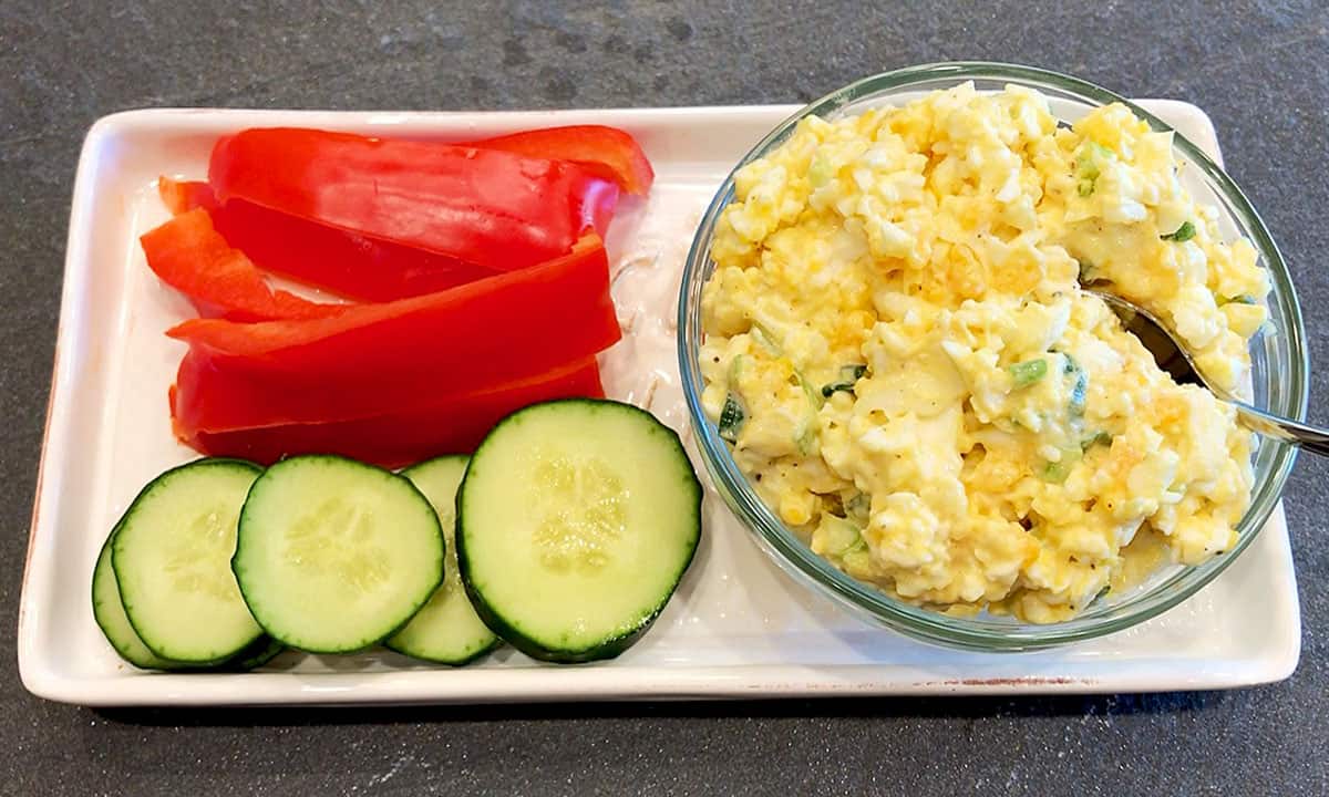 Egg salad is served with vegetables.