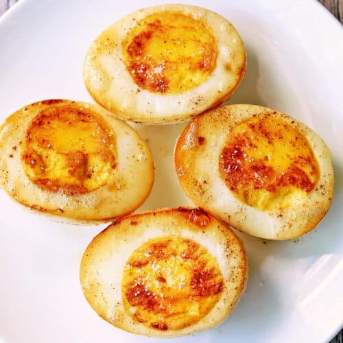 Fried boiled eggs are served on a white plate.