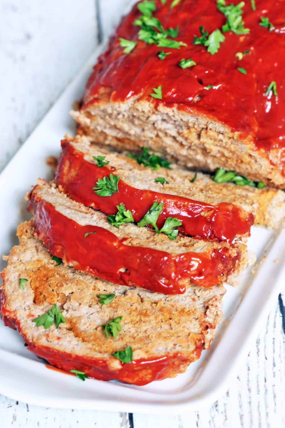 A sliced turkey meatloaf is served on a white serving plate. 