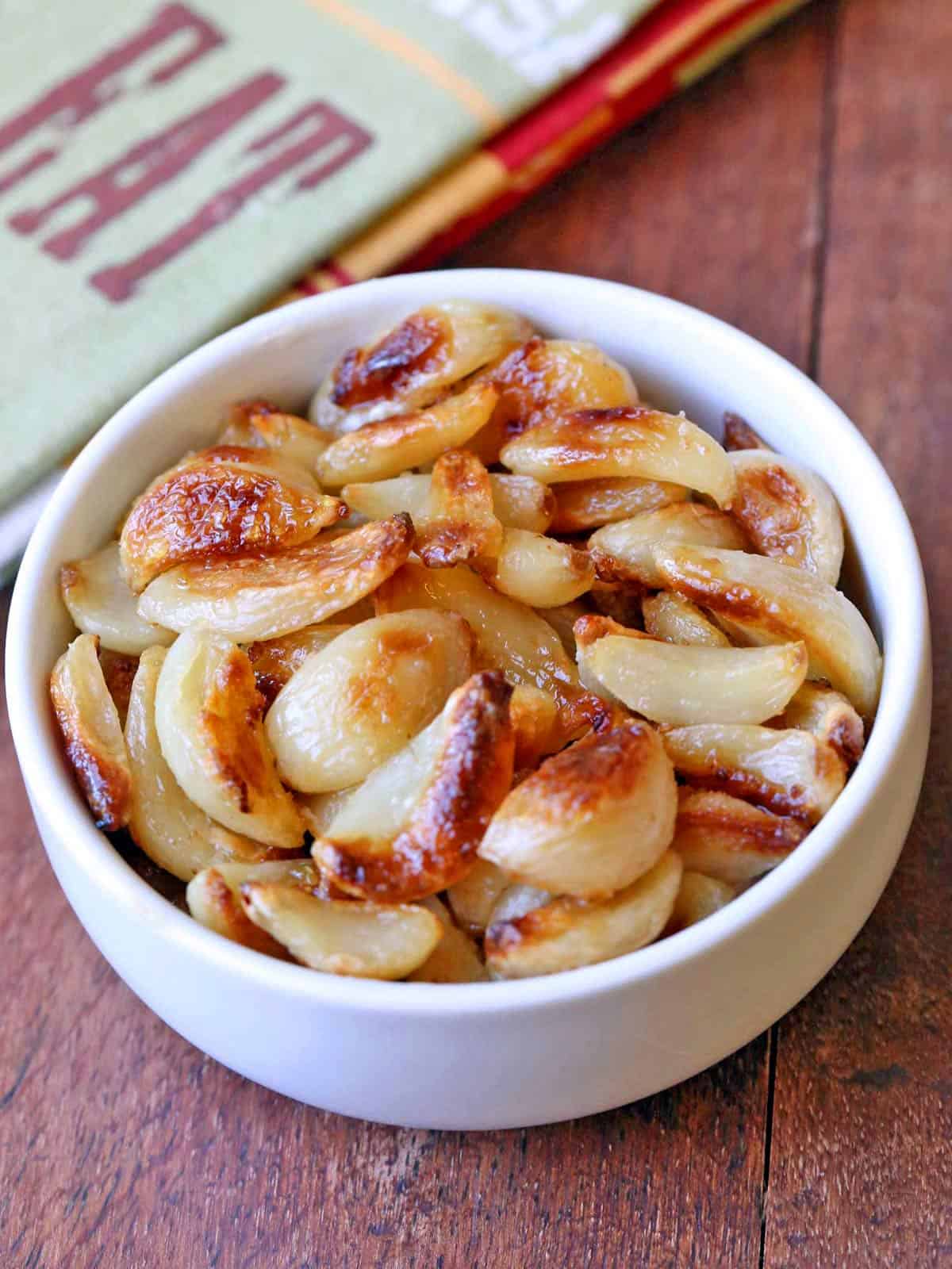 Roasted garlic cloves are served in a white bowl.