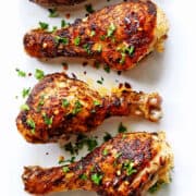 Spicy drumsticks are served on a white plate.