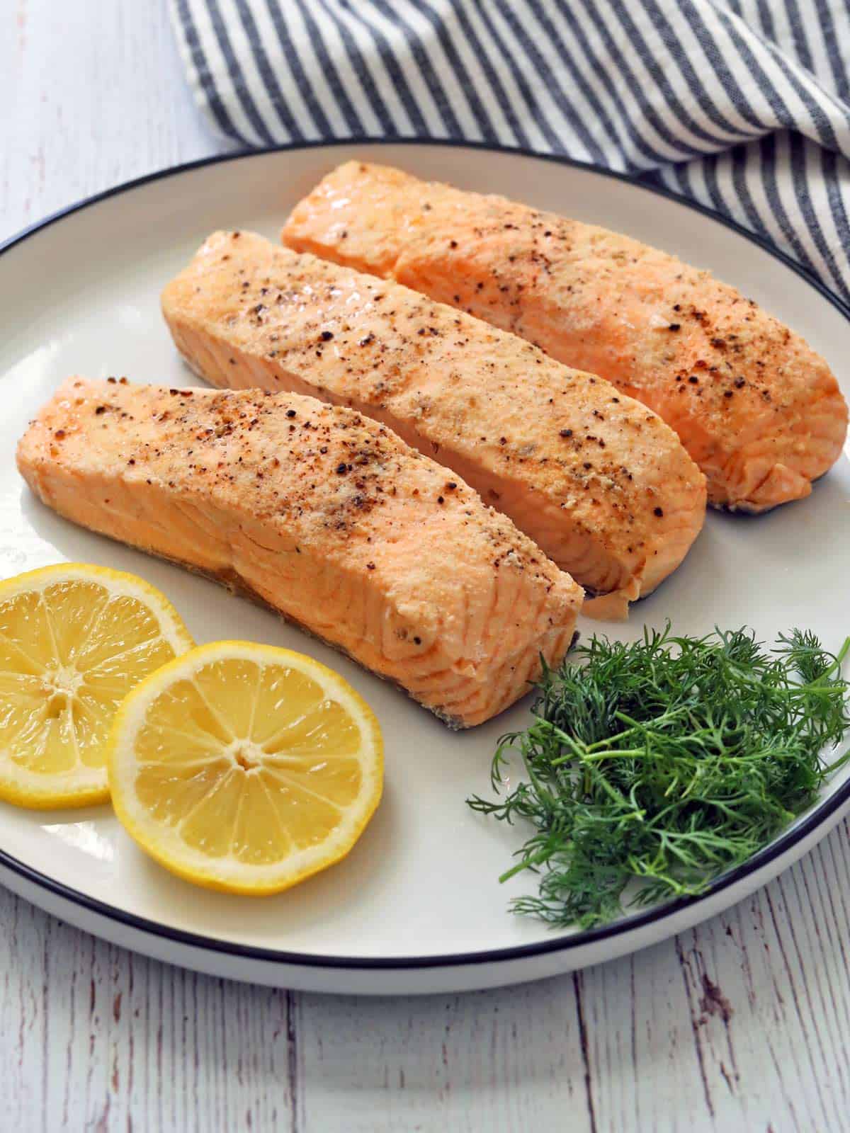 Poached salmon is served on a white plate.