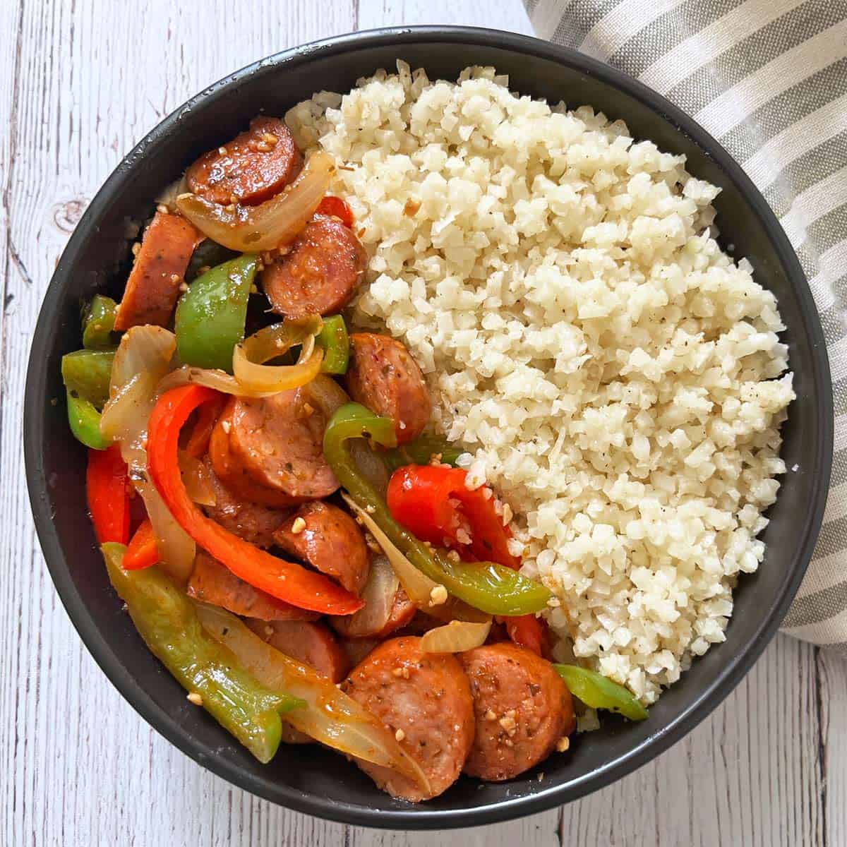 Sausage and peppers are served with cauliflower rice.