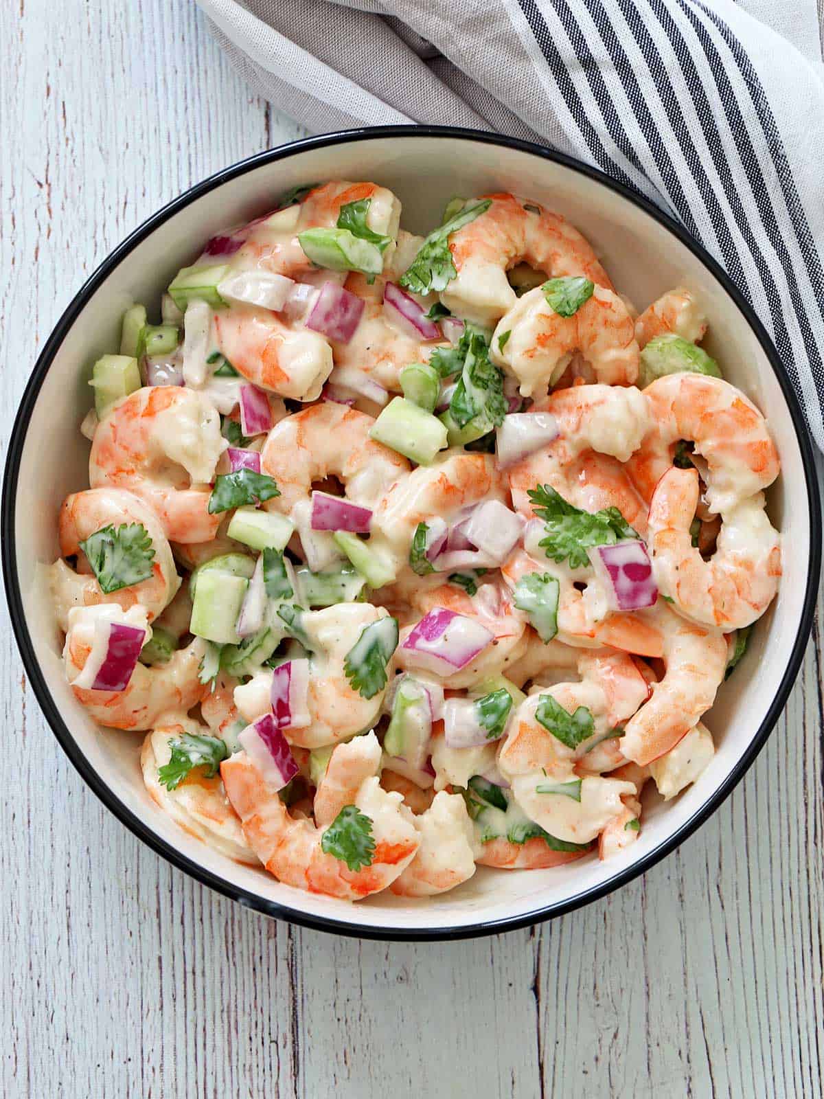 Shrimp salad is served in a white bowl.