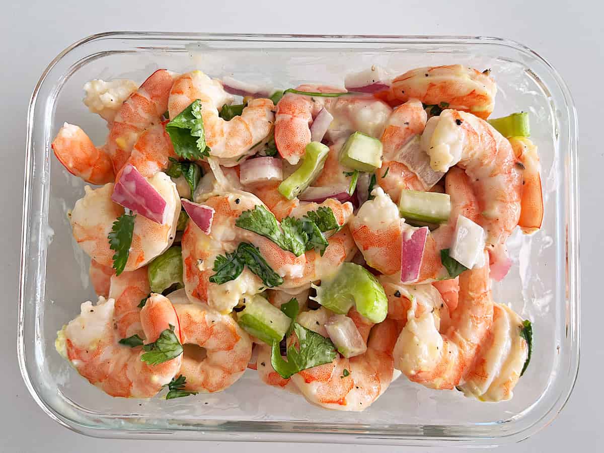 Shrimp salad leftovers are kept in a glass food storage container.