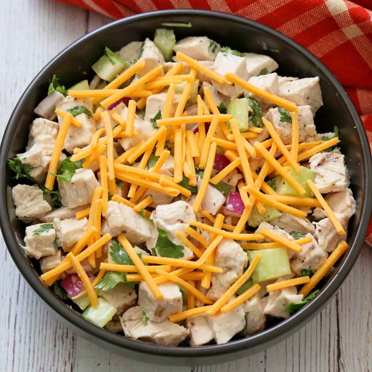 Turkey salad is topped with shredded cheddar.