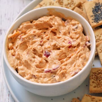 Pimento cheese is served in a white bowl with crackers on the side.