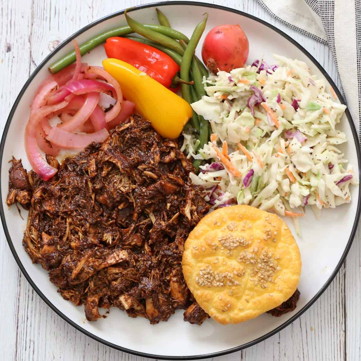 Pulled chicken is served with cloud bread, coleslaw, and pickles.