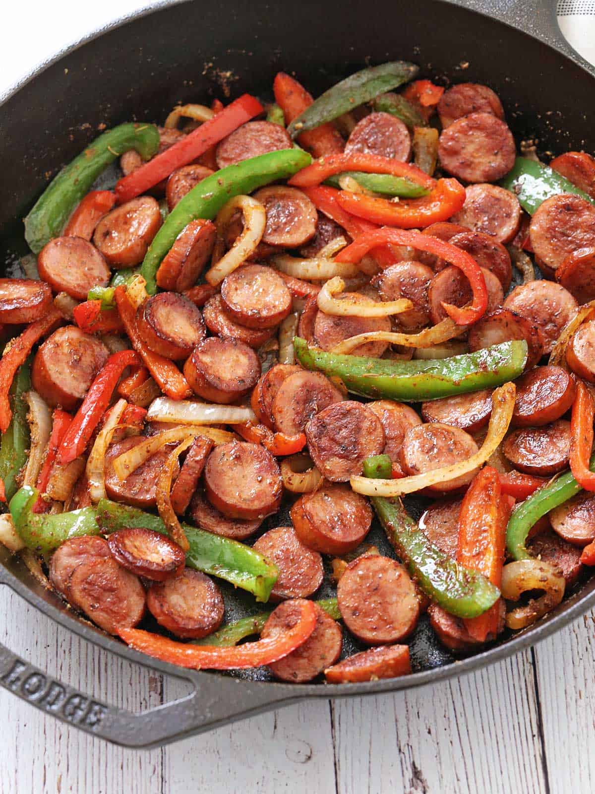 Sausage and peppers are served in a dark skillet.