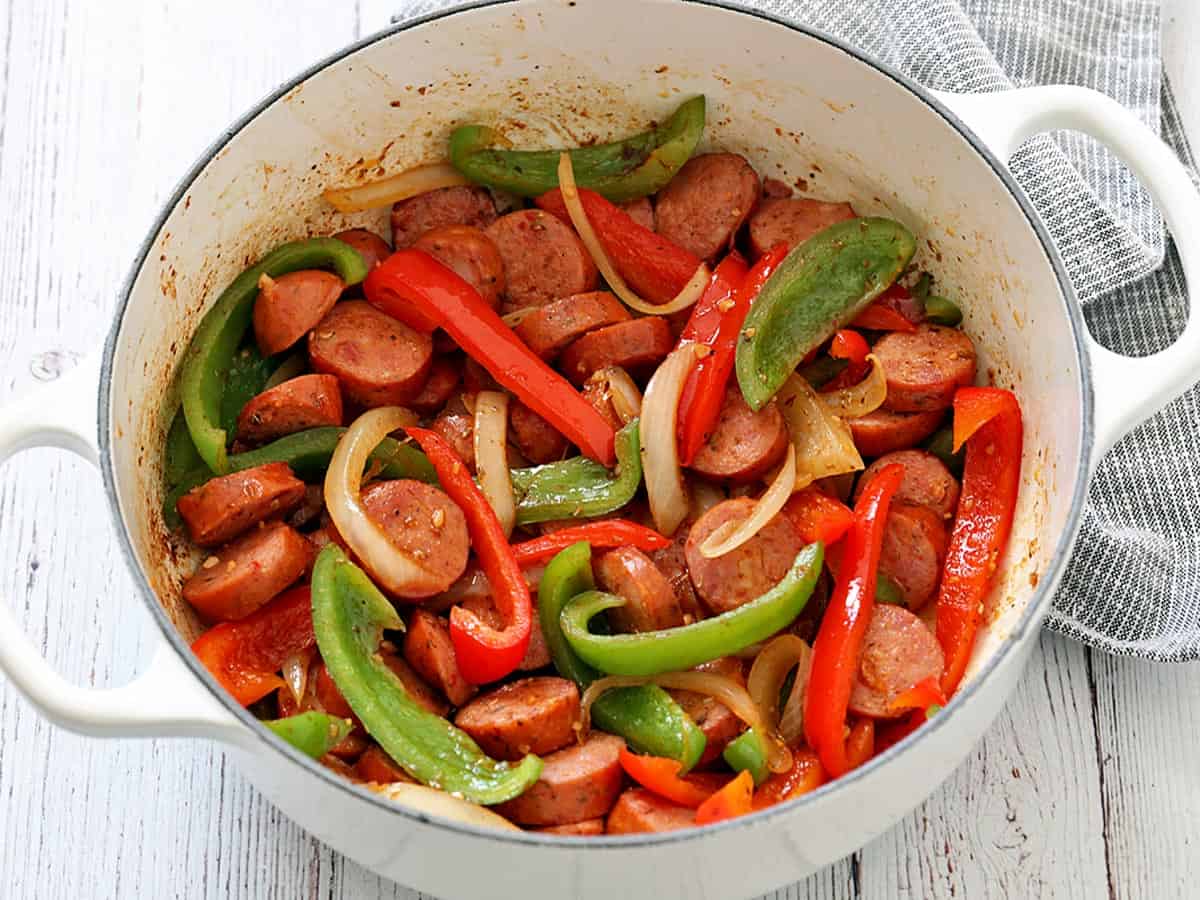 Sausage and peppers in an enameled cast-iron saucepan.