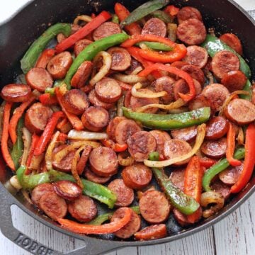 Sausage and peppers are served in a cast-iron skillet.