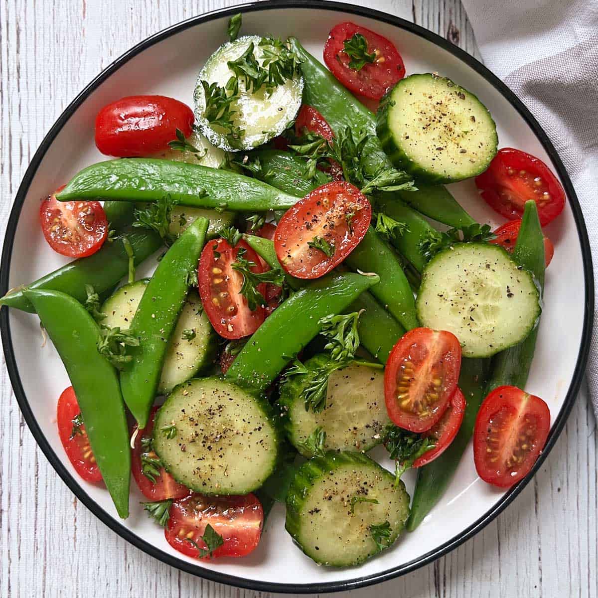 Sugar snap peas leftovers are added to a cucumber tomato salad.