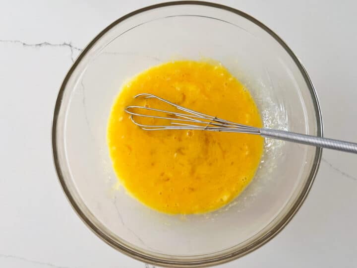 Whisking the eggs, butter, vinegar, and salt.