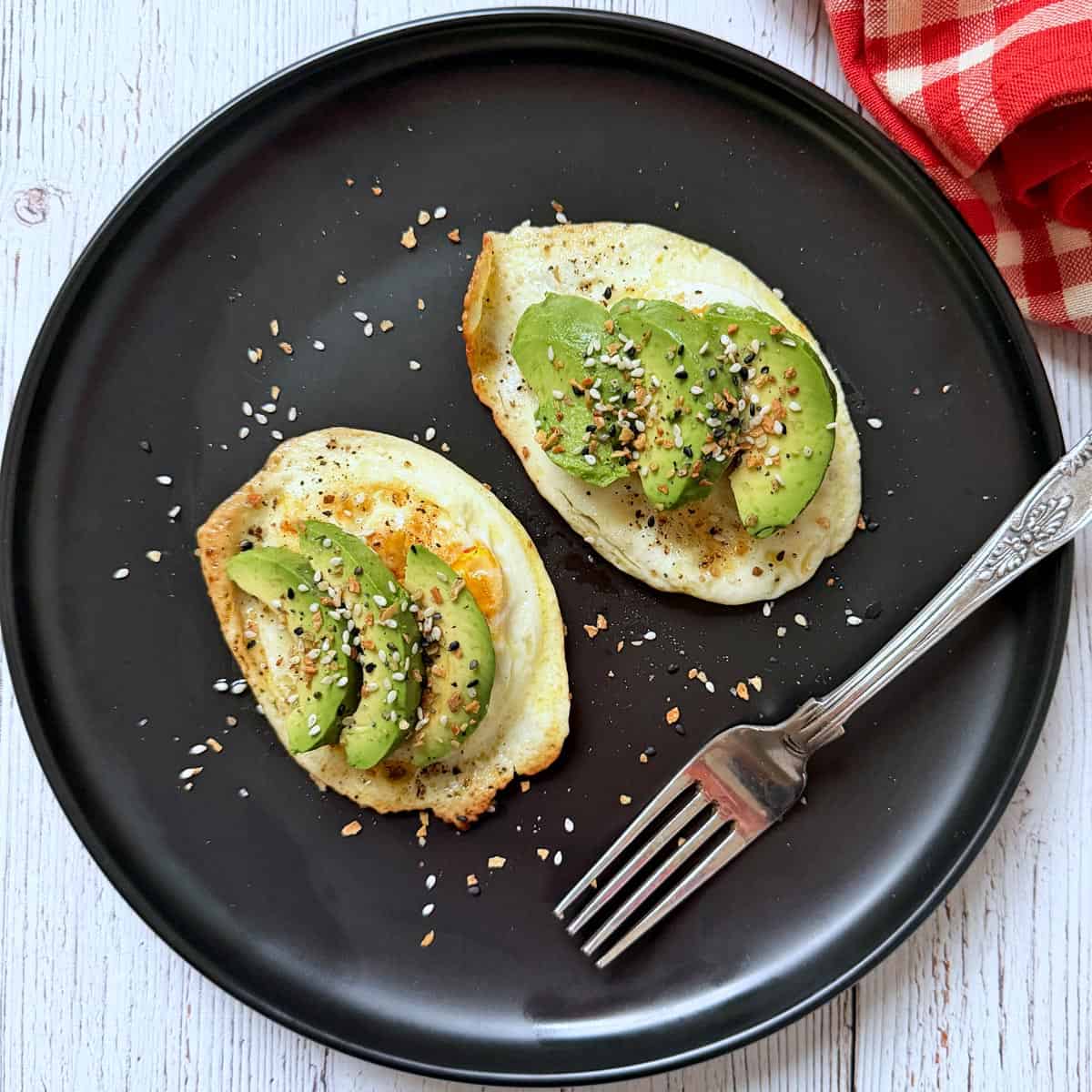 Fried eggs are topped with avocado and bagel seasoning.