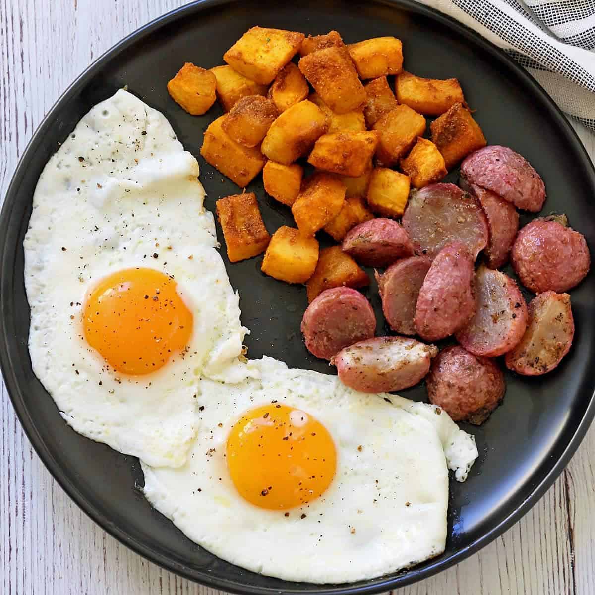 Fried eggs cooked in oil and served with roasted pumpkin and radishes.