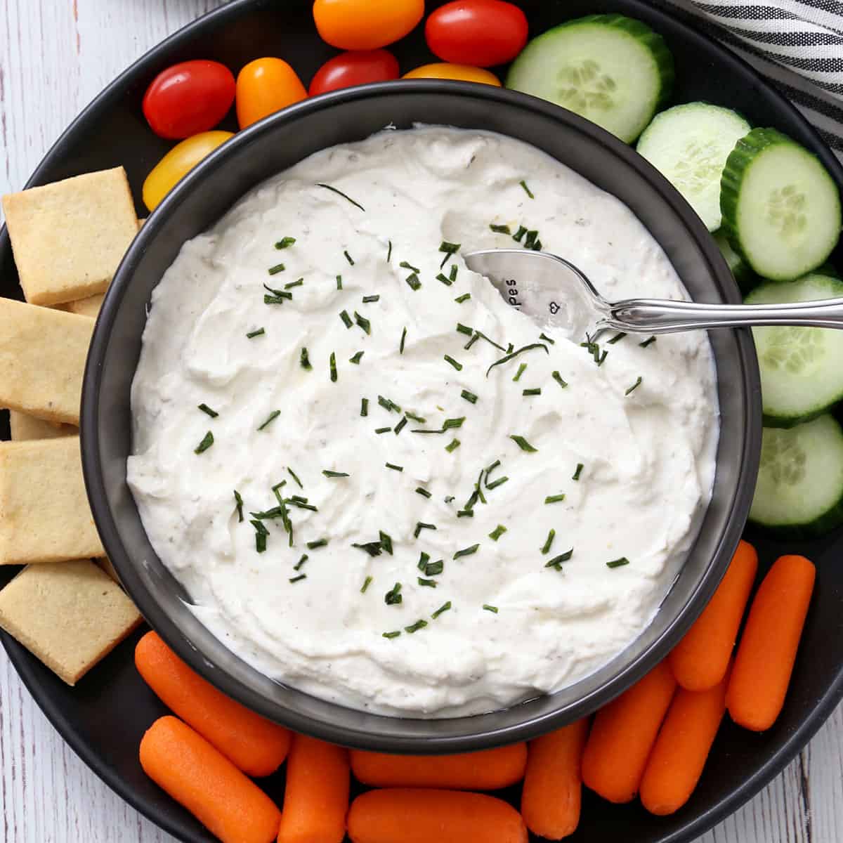 Greek yogurt dip is served with crackers and veggies.