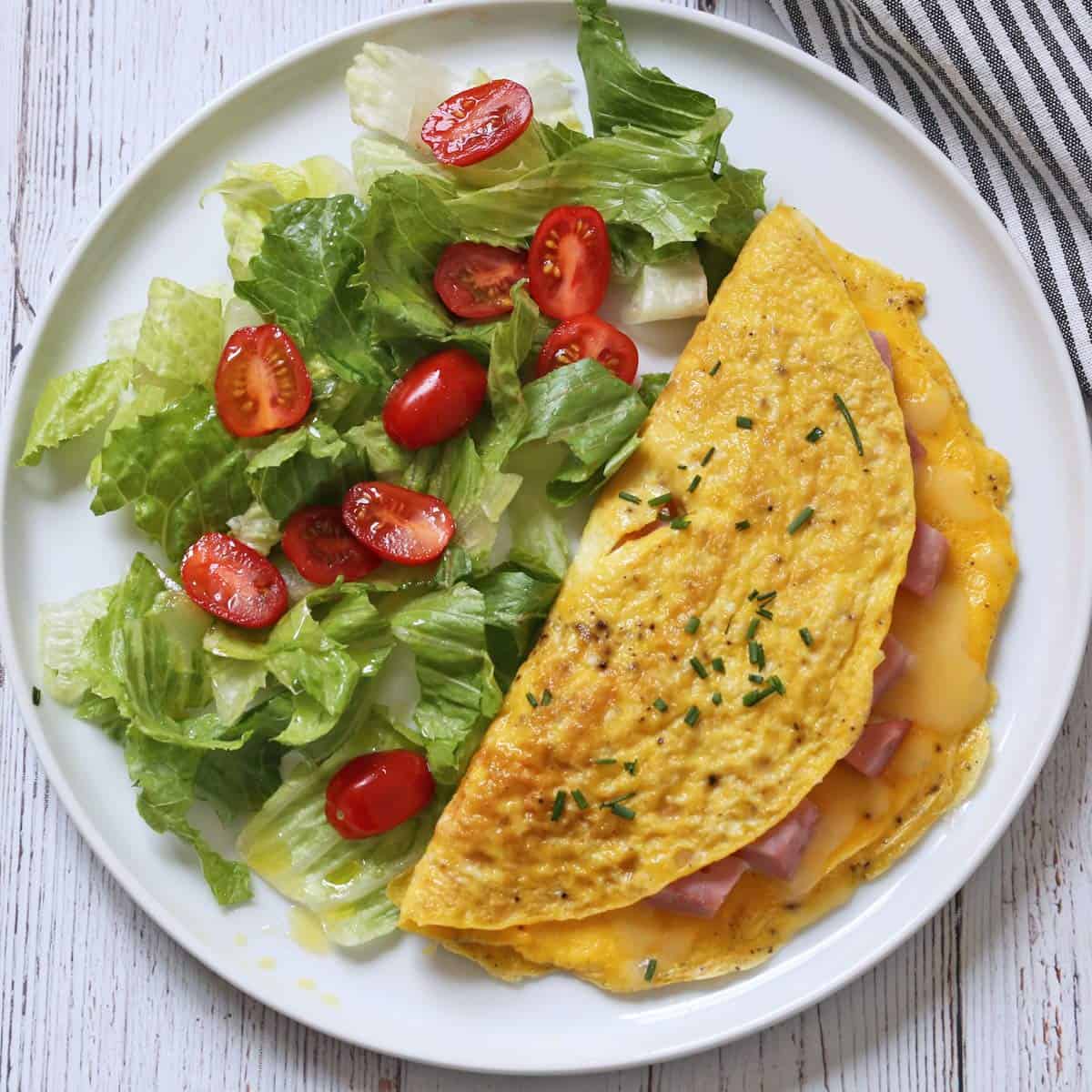 A ham and cheese omelette is served with a salad.