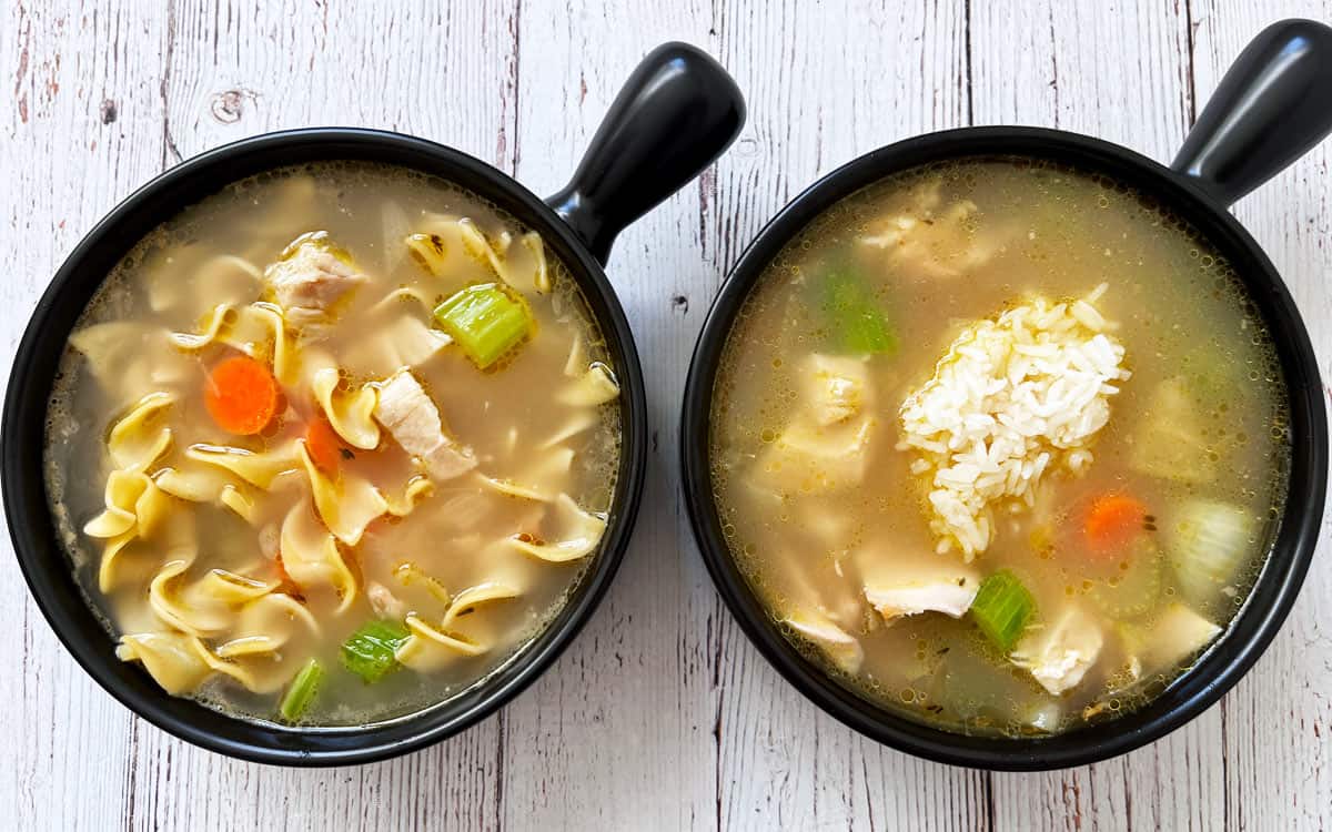 Two bowls of turkey soup, one with egg noodles and one with rice.