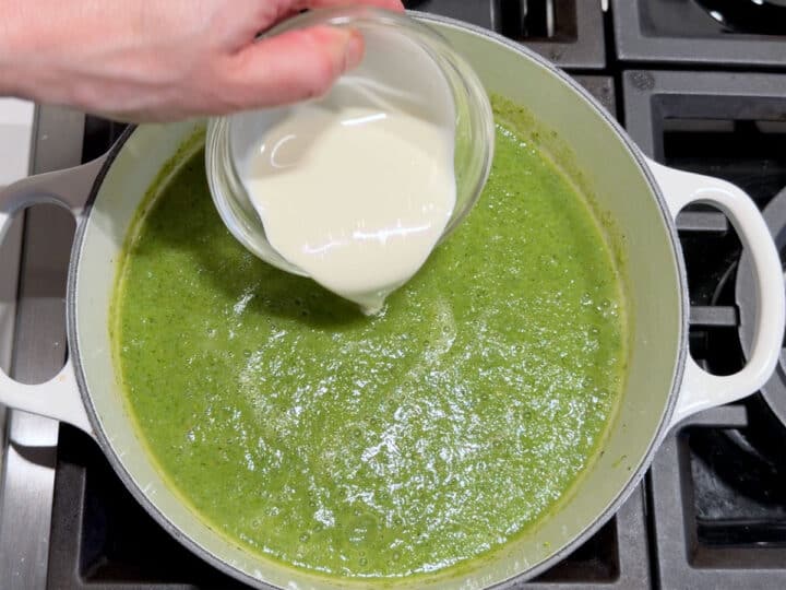 Adding heavy cream to the soup.
