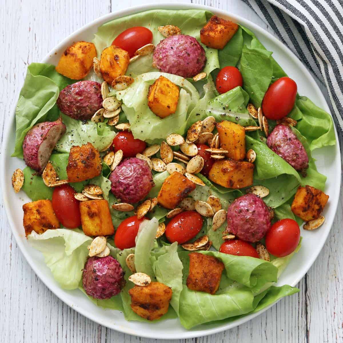 An autumn salad with roasted radishes, pumpkin, and pumpkin seeds.