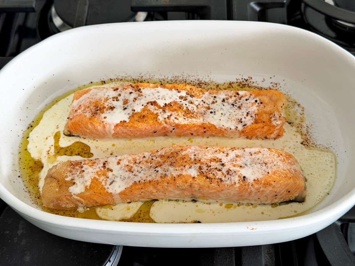Baked salmon in the pan was topped with heavy cream.