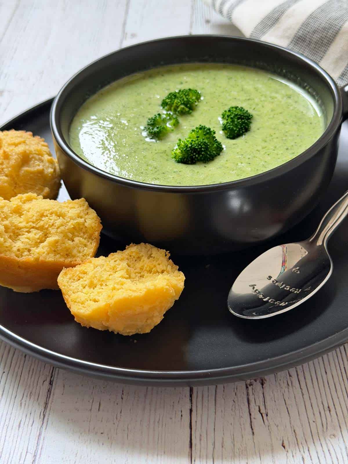 Broccoli soup is served with cornbread muffins.