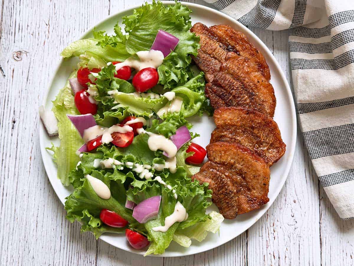 Pork belly strips are served with a salad.
