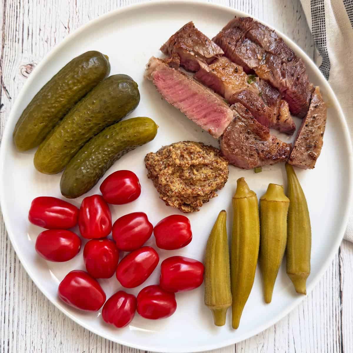 Leftover ribeye steak is served with tomatoes, pickles, and mustard.