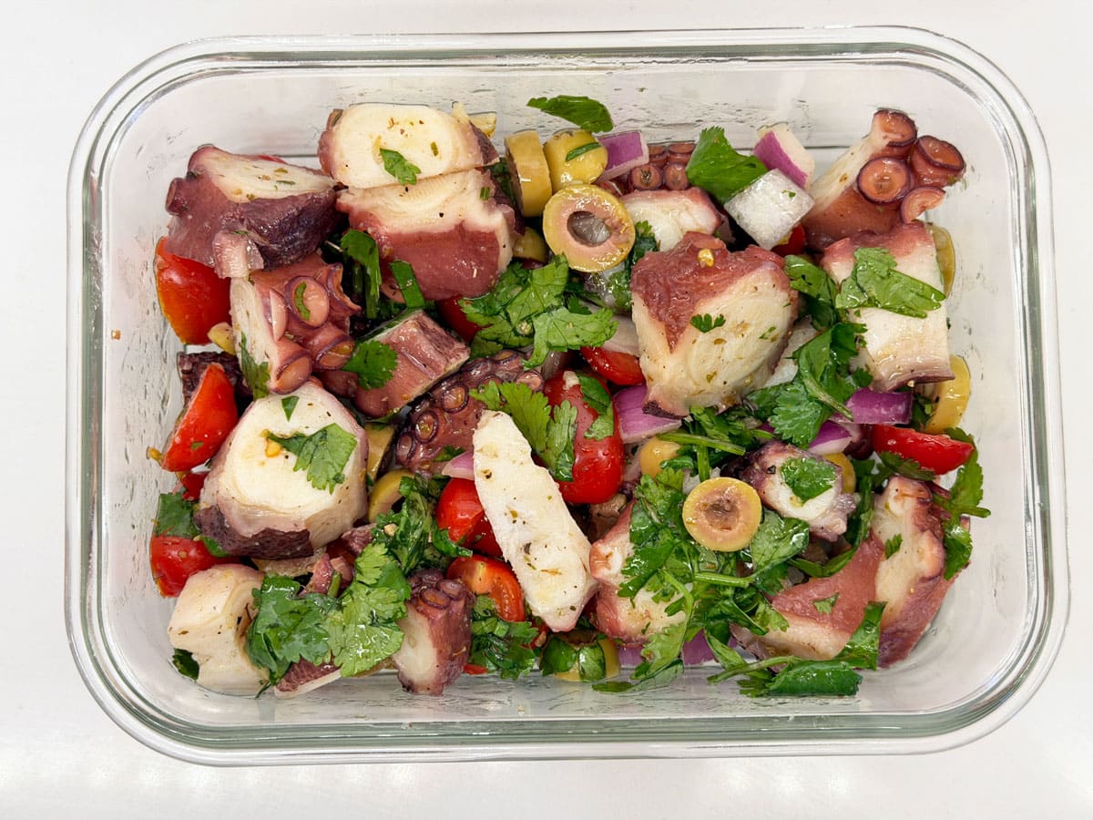 Octopus salad is stored in a glass container.