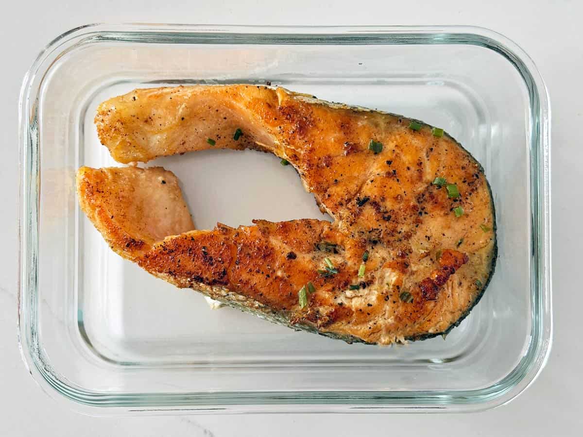 Salmon steak is stored in a glass container.